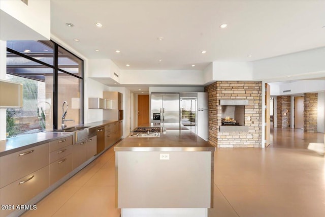 kitchen featuring gray cabinetry, a fireplace, stainless steel appliances, sink, and a spacious island