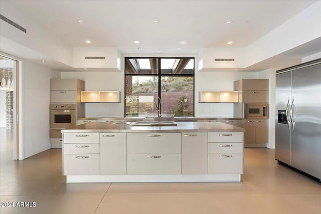 kitchen with sink, built in appliances, and white cabinets