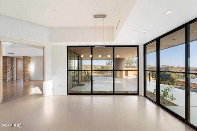 unfurnished room with expansive windows, concrete floors, and ornate columns