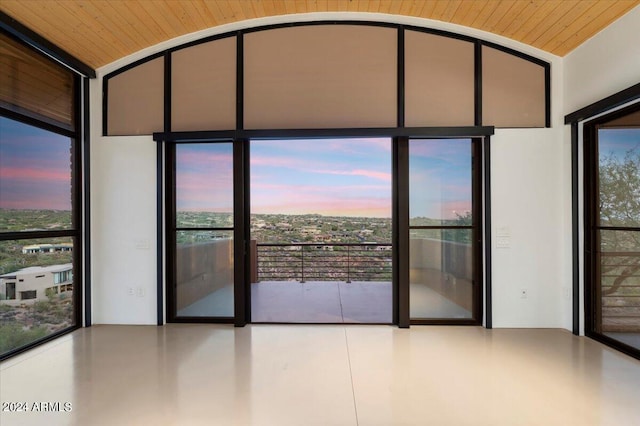 empty room featuring a wall of windows, lofted ceiling, and wooden ceiling