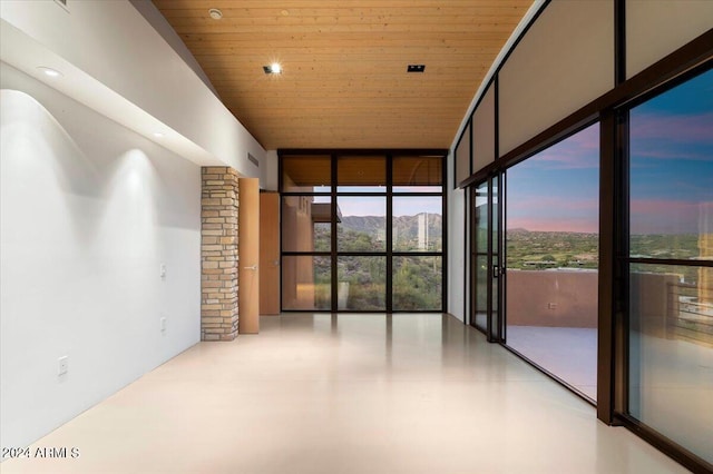 spare room with floor to ceiling windows, wooden ceiling, and a mountain view