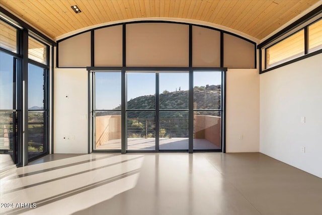 spare room with wood ceiling, a wall of windows, and plenty of natural light