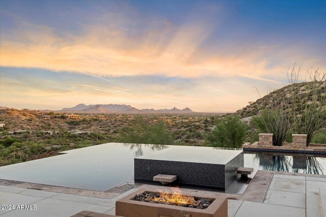 patio terrace at dusk featuring a fire pit and a mountain view