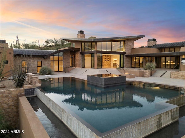 back house at dusk with a pool with hot tub and a patio area