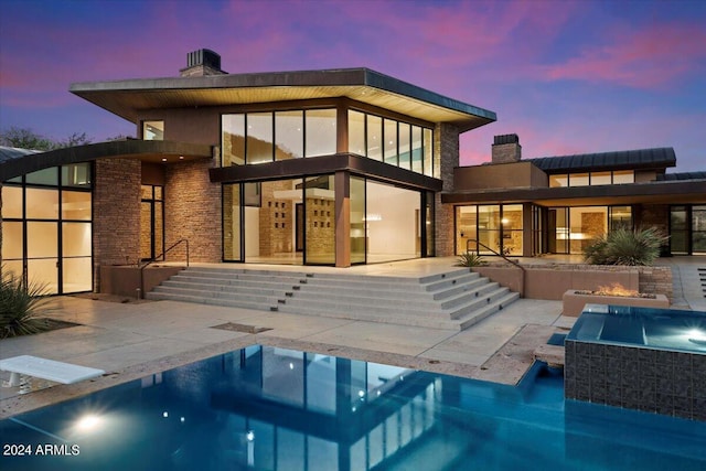 back house at dusk with a patio and a swimming pool with hot tub