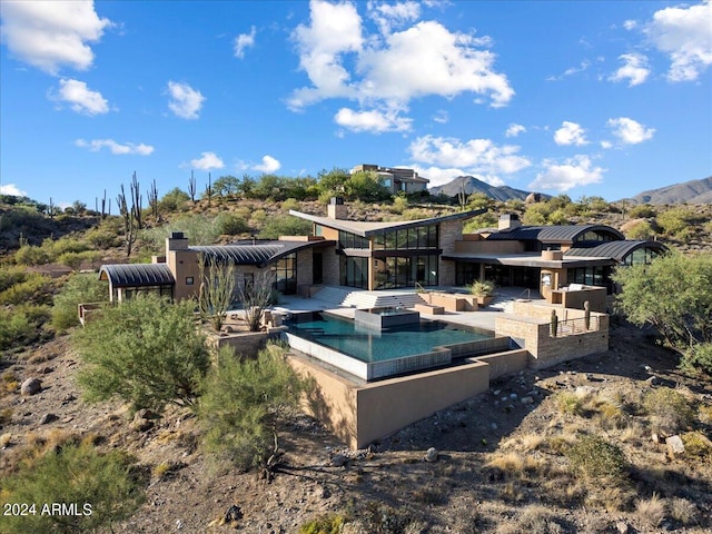 rear view of house featuring a pool with hot tub, a patio area, and a mountain view