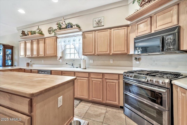 kitchen featuring light brown cabinetry, sink, range with two ovens, and light tile patterned floors