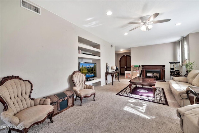 carpeted living room featuring ceiling fan and built in shelves