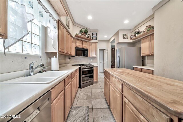 kitchen featuring sink, light tile patterned floors, stainless steel appliances, and wood counters