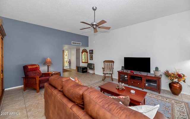 living room featuring lofted ceiling, ceiling fan, light tile patterned floors, and a textured ceiling