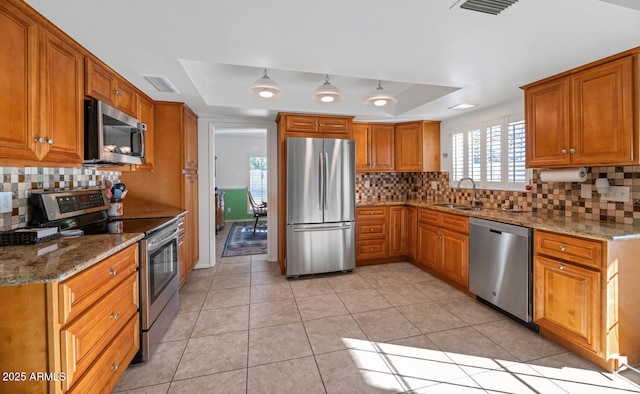 kitchen featuring a raised ceiling, light stone countertops, sink, and appliances with stainless steel finishes