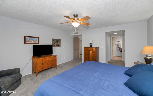 bedroom with ceiling fan, light colored carpet, and a textured ceiling