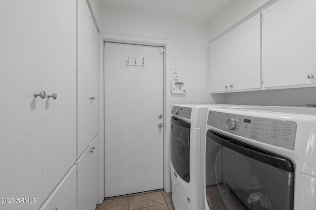 laundry area featuring washer and clothes dryer, cabinets, and light tile patterned floors