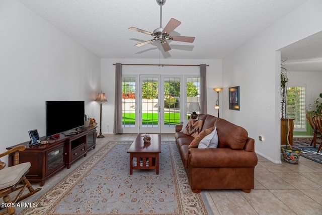 tiled living room featuring ceiling fan, a textured ceiling, and french doors