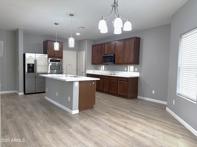 kitchen featuring light wood-style flooring, appliances with stainless steel finishes, light countertops, a sink, and baseboards
