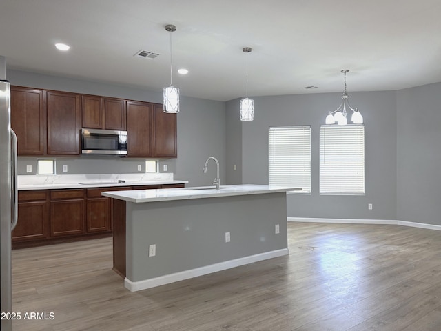 kitchen featuring stainless steel microwave, light wood-type flooring, light countertops, and visible vents