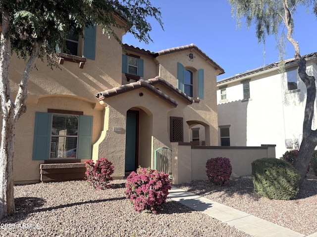 mediterranean / spanish house with a gate, a tile roof, stucco siding, and a fenced front yard