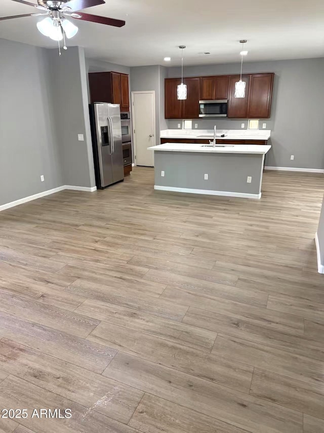 kitchen with light countertops, a ceiling fan, appliances with stainless steel finishes, and baseboards