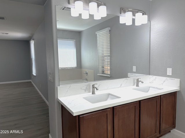 bathroom with double vanity, wood finished floors, baseboards, and a sink