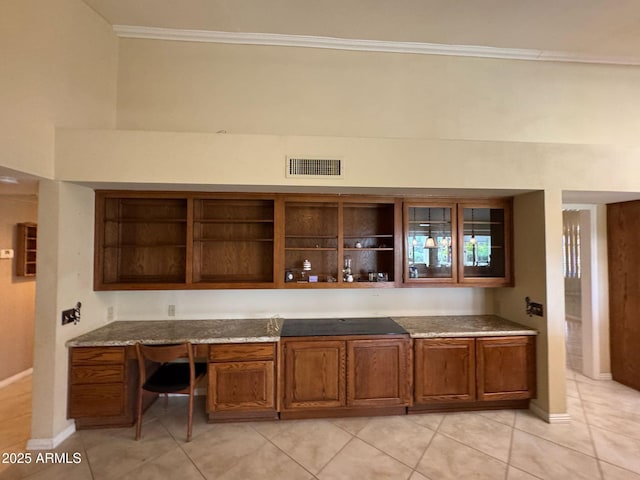 kitchen featuring brown cabinets, open shelves, built in desk, visible vents, and ornamental molding