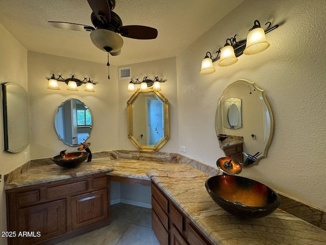 full bathroom featuring tile patterned flooring, vanity, a textured ceiling, a ceiling fan, and visible vents