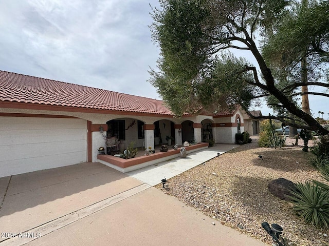 mediterranean / spanish-style house featuring an attached garage, stucco siding, a tiled roof, and concrete driveway