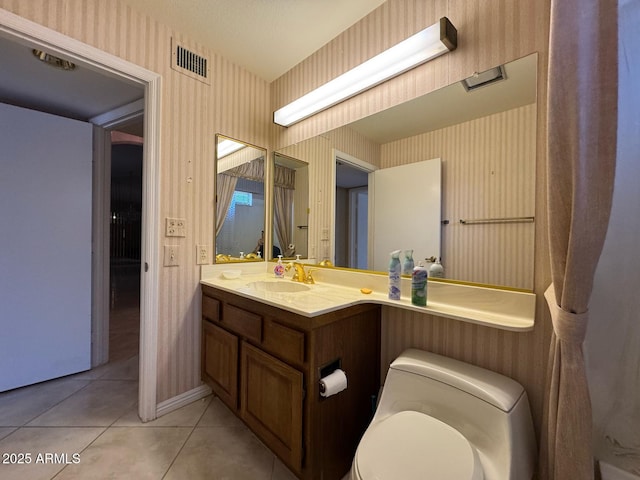 half bathroom featuring vanity, toilet, tile patterned floors, wallpapered walls, and visible vents