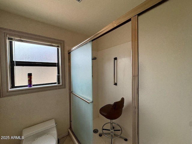 full bathroom featuring baseboards, toilet, and a shower stall