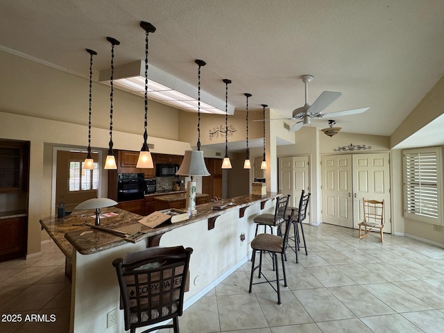 kitchen with lofted ceiling, a breakfast bar, dark stone countertops, light tile patterned floors, and black appliances