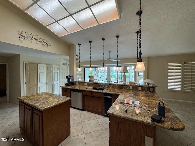 kitchen with pendant lighting, stone counters, light tile patterned floors, and dishwasher