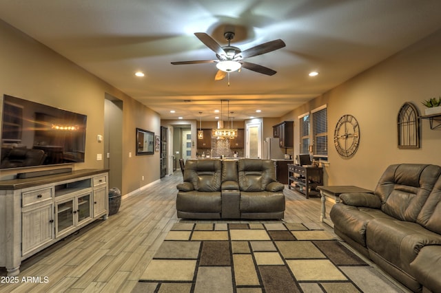 living room with light hardwood / wood-style flooring and ceiling fan with notable chandelier