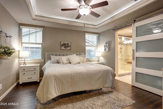 bedroom featuring ensuite bath, a barn door, ceiling fan, dark hardwood / wood-style floors, and a tray ceiling