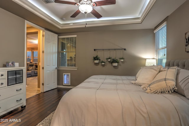 bedroom featuring ceiling fan, a tray ceiling, crown molding, and dark hardwood / wood-style floors