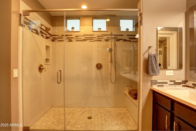 bathroom with a shower with door, vanity, and decorative backsplash