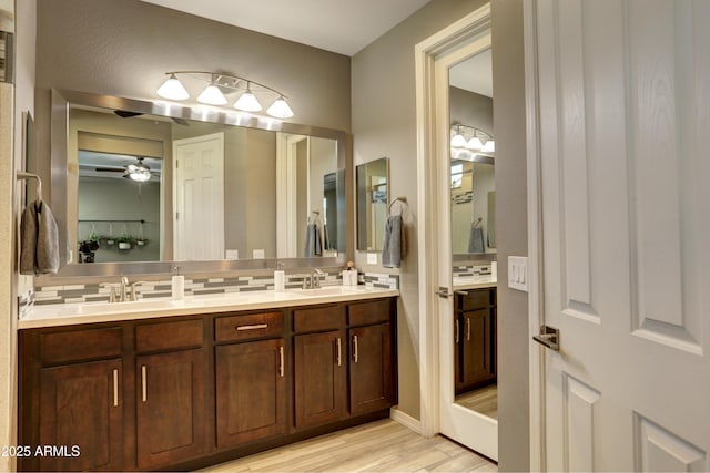 bathroom with wood-type flooring, vanity, ceiling fan, and tasteful backsplash