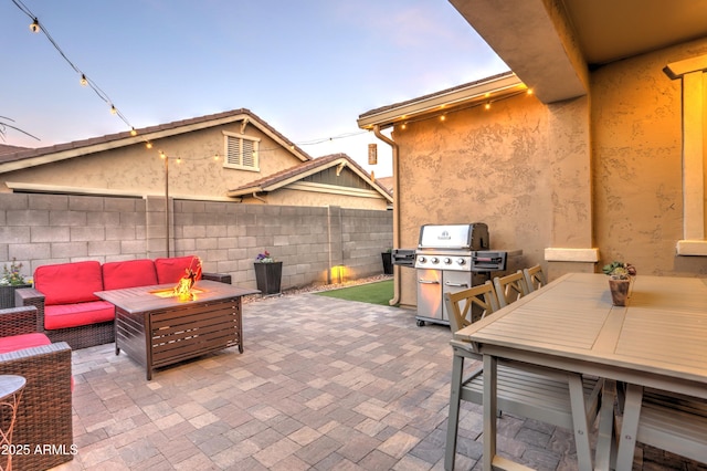 patio terrace at dusk with an outdoor living space with a fire pit and a grill