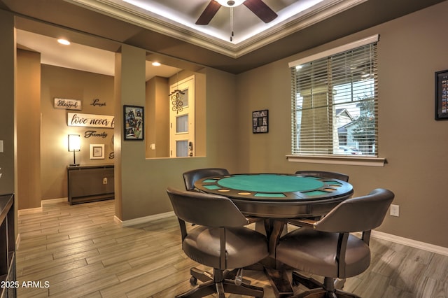 playroom featuring ceiling fan, light wood-type flooring, ornamental molding, and a tray ceiling