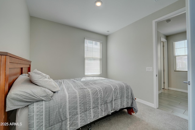 bedroom featuring light colored carpet, baseboards, and multiple windows
