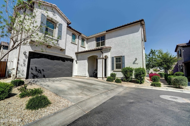 mediterranean / spanish house featuring a tile roof, an attached garage, driveway, and stucco siding