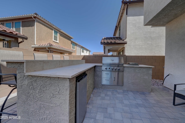 view of patio featuring fence, a grill, and exterior kitchen