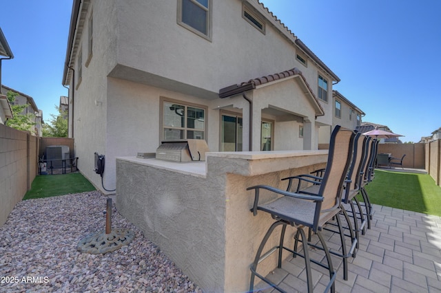 back of property featuring area for grilling, a patio, a fenced backyard, and stucco siding