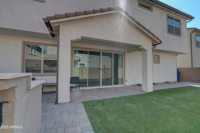 back of property featuring a tiled roof, a patio, a lawn, and stucco siding