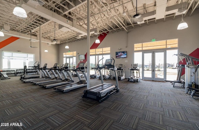 gym with carpet flooring, a towering ceiling, visible vents, and french doors
