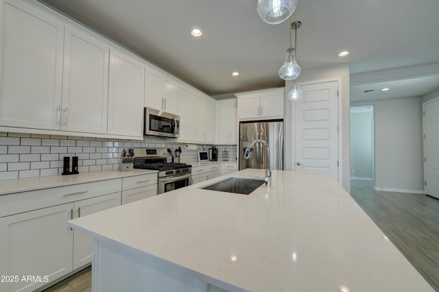 kitchen featuring light wood-style floors, tasteful backsplash, white cabinetry, appliances with stainless steel finishes, and a sink
