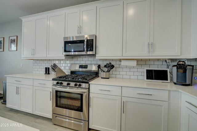 kitchen featuring decorative backsplash, light countertops, white cabinetry, and stainless steel appliances