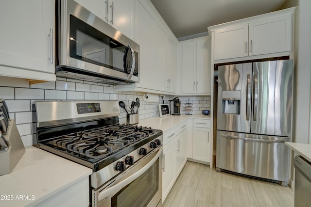 kitchen with tasteful backsplash, appliances with stainless steel finishes, light stone counters, and white cabinetry