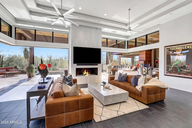 living room with ceiling fan, a fireplace, a raised ceiling, and a healthy amount of sunlight