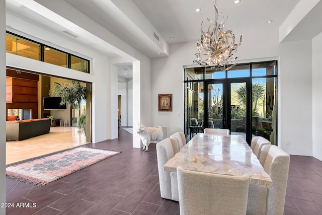 dining space with french doors, a high ceiling, and a notable chandelier