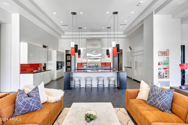 living room featuring a tray ceiling, sink, and a high ceiling