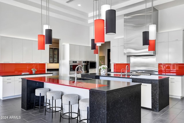 kitchen with pendant lighting, sink, white cabinetry, and a large island with sink